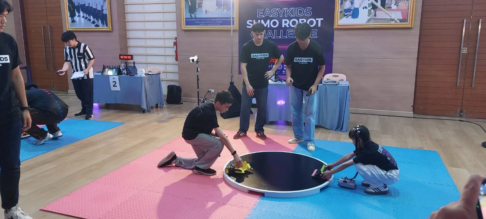 Competitors placing their sumo robots into the ring before a match